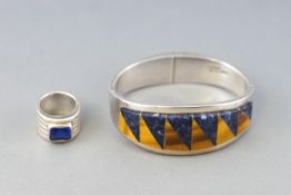 A Mexican white metal double hinged bangle, st with a panel of sodalite and tigers eye,
