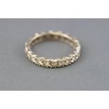 A white metal full eternity ring set with colourless synthetic spinel.