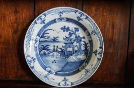 An 18th century English Delft charger painted with figures on a bridge, 34.