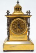 A Victorian brass columned clock with pierced pagaoda style top over a rose window Arabic dial,