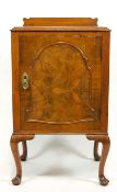 A walnut bed side cabinet with arched panel to door and cabriole legs,