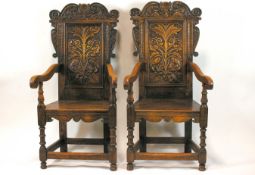 A pair of 17th century style oak chairs, each with carved panelled backs,