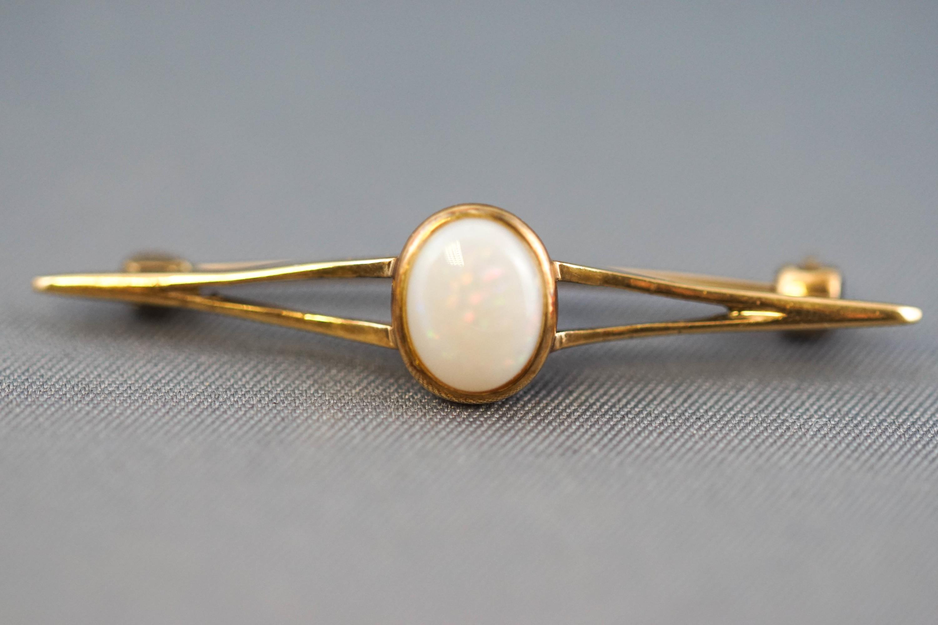 A collection of jewellery to include: A yellow metal bar brooch centrally set with an oval cabochon