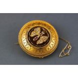 A yellow metal circular mourning brooch having an intricate filigree design and centrally finished