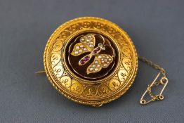 A yellow metal circular mourning brooch having an intricate filigree design and centrally finished