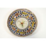 A Continental tin glazed charger, decorated with a central flower spray within various borders,