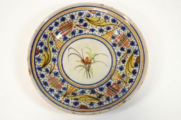 A Continental tin glazed charger, decorated with a central flower spray within various borders,