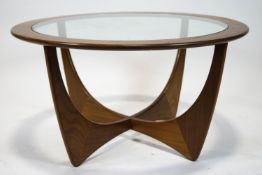 A G-plan teak and glass topped coffee table, of circular form with raised curved supports,