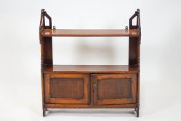 A Victorian mahogany hanging wall shelf, with two tiers above two panelled doors,