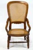 A 19th century mahogany elbow chair with caned seat and back on turned legs linked by stretchers,