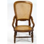 A 19th century mahogany elbow chair with caned seat and back on turned legs linked by stretchers,