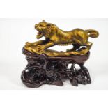 A carved hardstone tiger's eye figure of a snarling lion on a carved root wood stand,