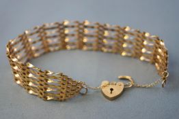 A yellow metal seven bar gate bracelet. Padlock and safety chain. Hallmarked 9ct gold, London, 1991.