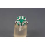 A white metal cluster ring set with a central square faceted cut emerald measuring approximately 5.