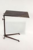 A 1930's iron and bakelite adjustable bed table/stand, the base with castors, 75cm high x 59.