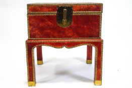 A red leather covered box on stand, with two brass handles and brass studs,