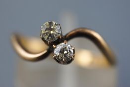 A yellow metal two stone crossover ring set with one old European cut diamond of approximately 0.