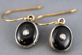 A yellow and whiter metal pair of drop earrings each having an oval pendant drop set with onyx and