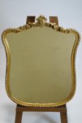 A carved gilt wood framed bevelled wall mirror of waisted form with foliate cresting in a rope work