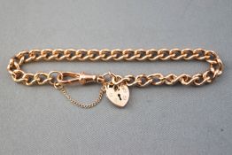 A rose metal curb link bracelet, having padlock safety chain and swivel clasp fittings.