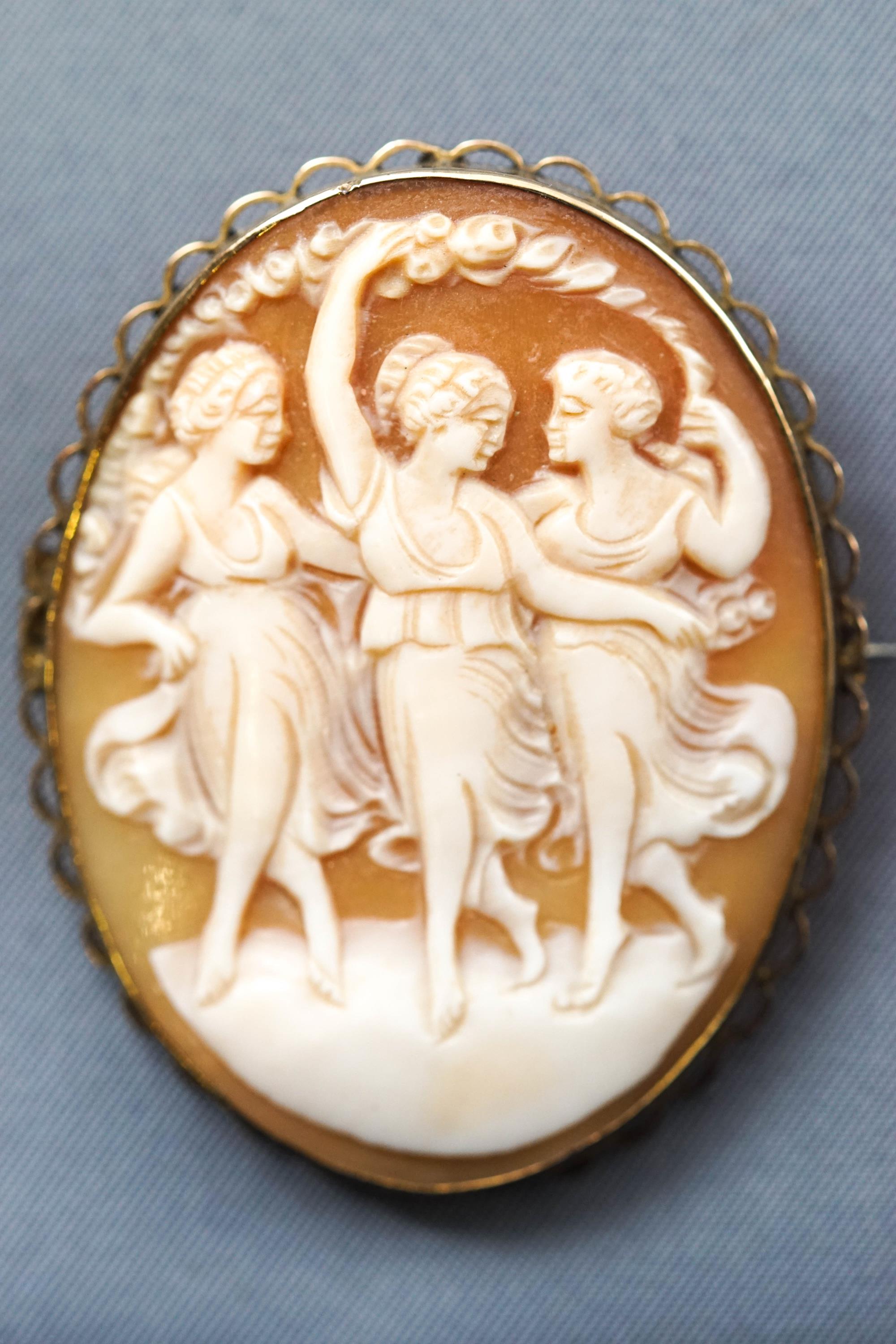 A yellow metal oval cameo brooch with base metal pin together with a pair of oval cameo screw clip