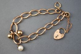 A yellow metal open link curb bracelet having two attached gold beads and one cultured pearl