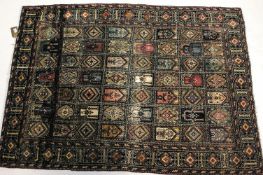 A silk rug, decorated with panels of Mihrabs and geometric designs within a diamond border ,