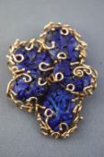 A yellow metal abstract scroll design wire brooch set with carved floral lapis lazuli (untested).