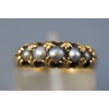 A yellow metal half hoop ring set with five graduated half pearls.