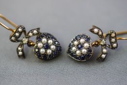 A yellow and white metal pair of drop earrings, styled as a heart design and set with sapphires,