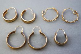 A collection of three pairs and one single yellow metal hoop earrings,