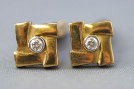 A yellow metal pair of cufflinks each having Tbar hinged fittings and set with a round faceted cut