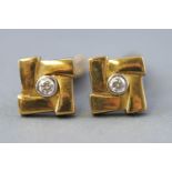 A yellow metal pair of cufflinks each having Tbar hinged fittings and set with a round faceted cut
