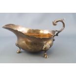 A silver sauce boat of traditional form with cut card edge and flying scroll handle to a bellied