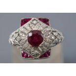 A white metal abstract ring principally set with a cushion faceted cut ruby estimated to weigh 1.