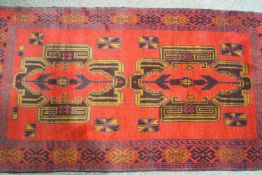 A Baluchi Herati rug with two large medallions on a red field within one wide border,