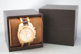 A rose metal Michael Kors Bradshaw wristwatch having a linked rose metal bracelet.