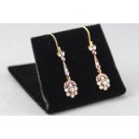 A yellow and white metal pair of drop earrings each set with commercial quality rubies and round