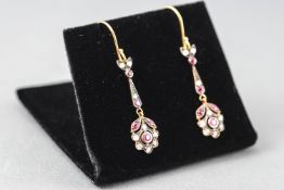 A yellow and white metal pair of drop earrings each set with commercial quality rubies and round