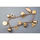 A yellow metal curb link bracelet having eleven assorted charms.