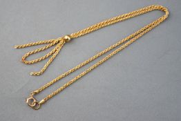 A yellow metal rope link necklace stylized as a centrepiece bead with four drop tassels.