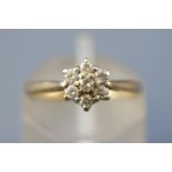 A yellow metal cluster ring set with seven round brilliant cut diamonds. Stamped total weight of 0.