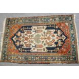 A Caucasian rug with stylized flowers on a blue ground with red spandrels and one wide border,