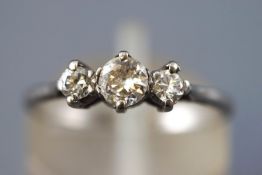 A white metal diamond ring. Set with three graduated round brilliant cut diamonds.