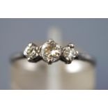 A white metal diamond ring. Set with three graduated round brilliant cut diamonds.