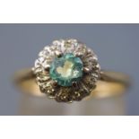 A yellow and white metal cluster ring set with a central blue zircon (substantially chipped) and
