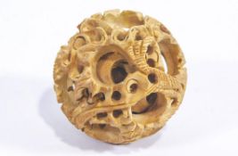 A carved wood devil's work ball with writhing dragon designs,