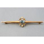 A yellow metal bar brooch with central motif set with a rectangular faceted cut aquamarine and seed