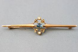 A yellow metal bar brooch with central motif set with a rectangular faceted cut aquamarine and seed