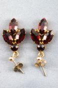 A yellow metal pair of drop earrings each set with faceted cut red paste stones.